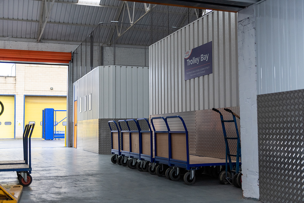 A large loading bay with trolleys lined up against the wall.